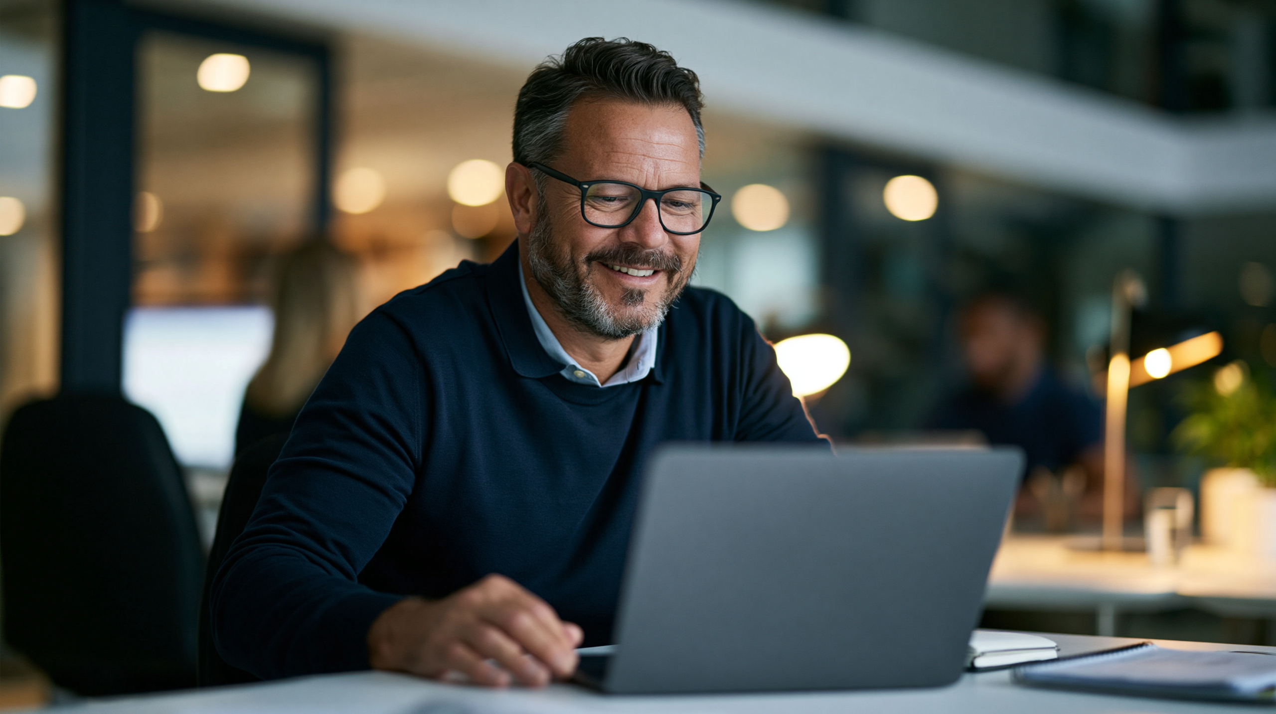 Profissional sorrindo enquanto acessa um laptop no escritório